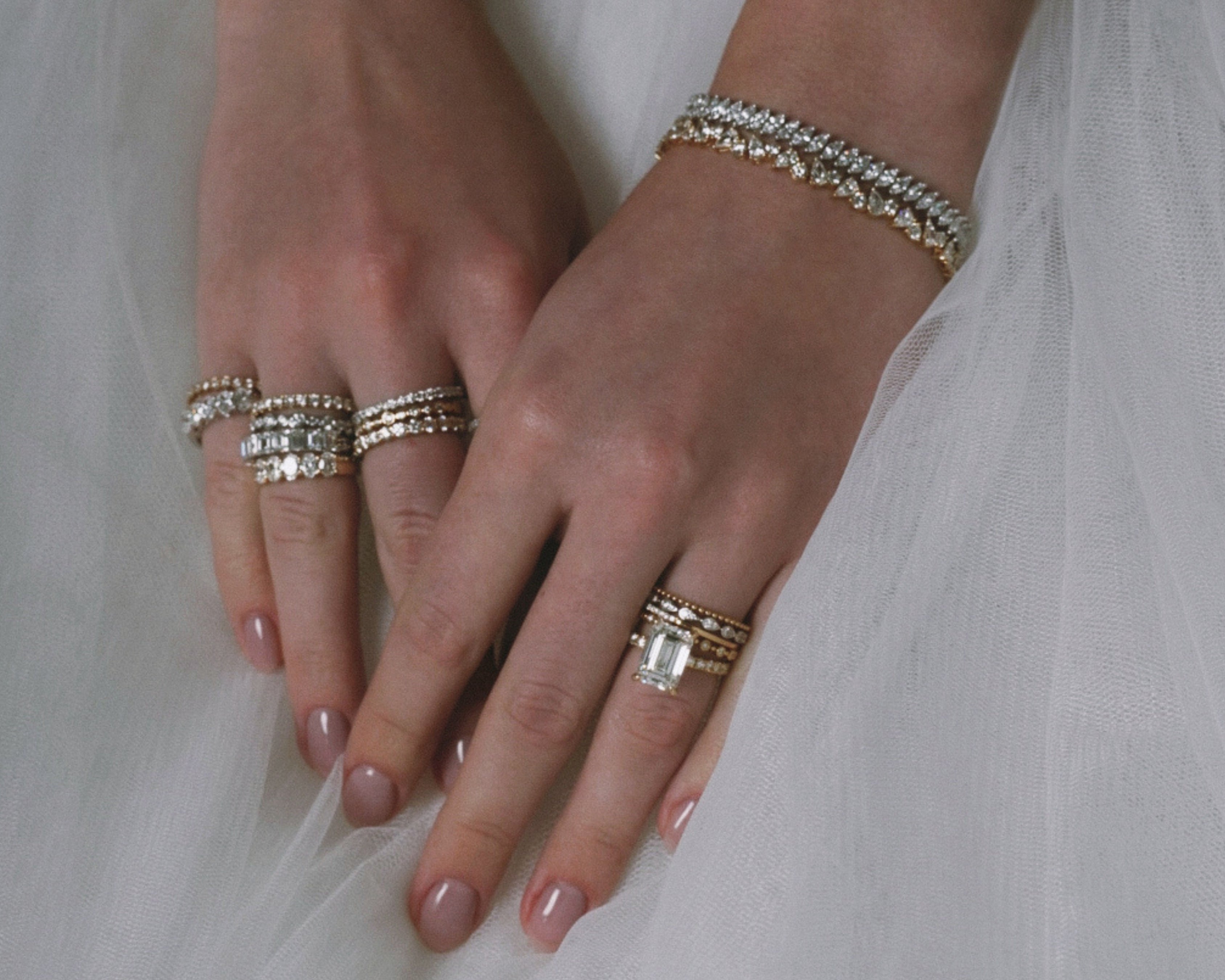 Close-up of hands with multiple rings and bracelets on a white background