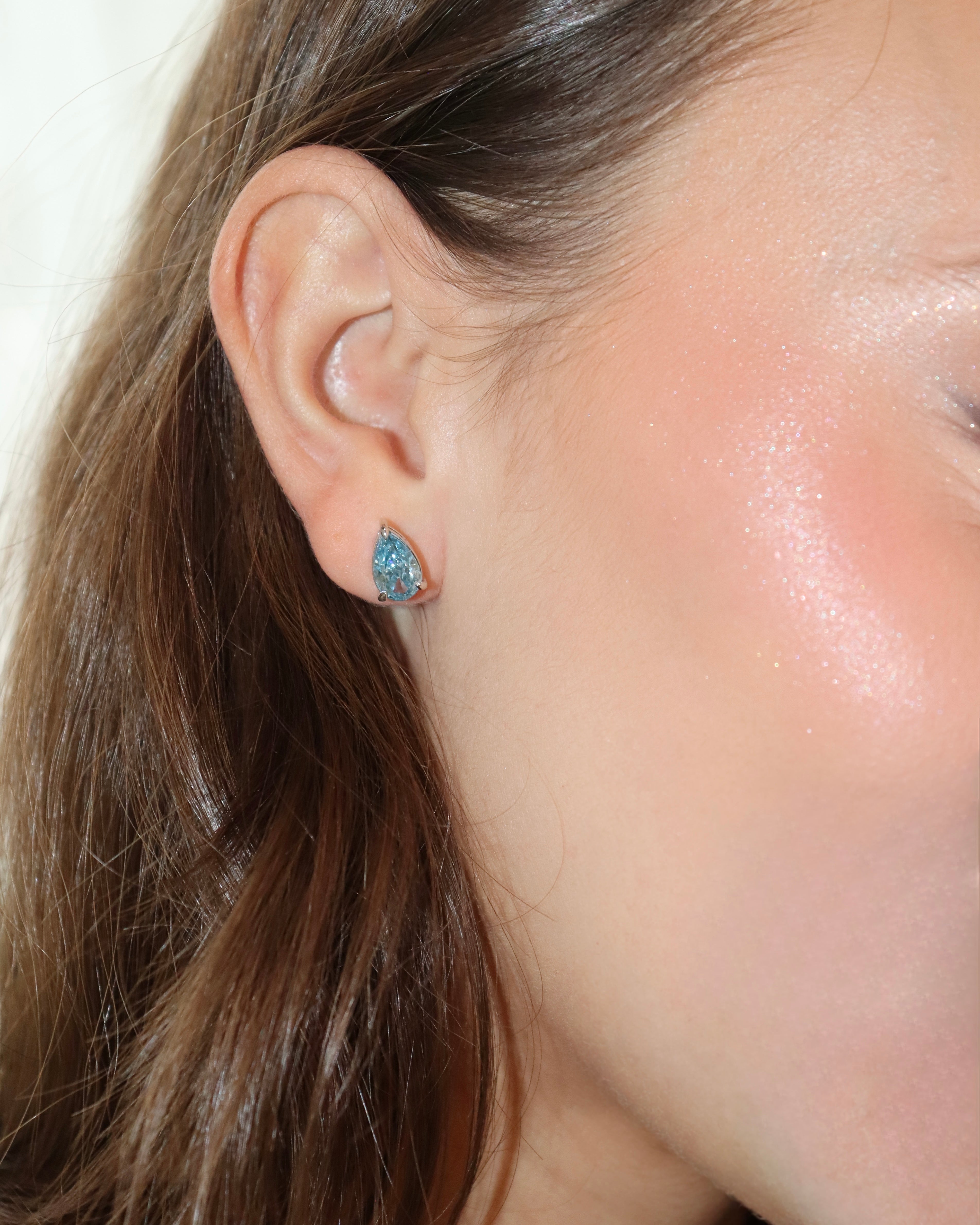 Close-up of a woman wearing turquoise stud earrings.