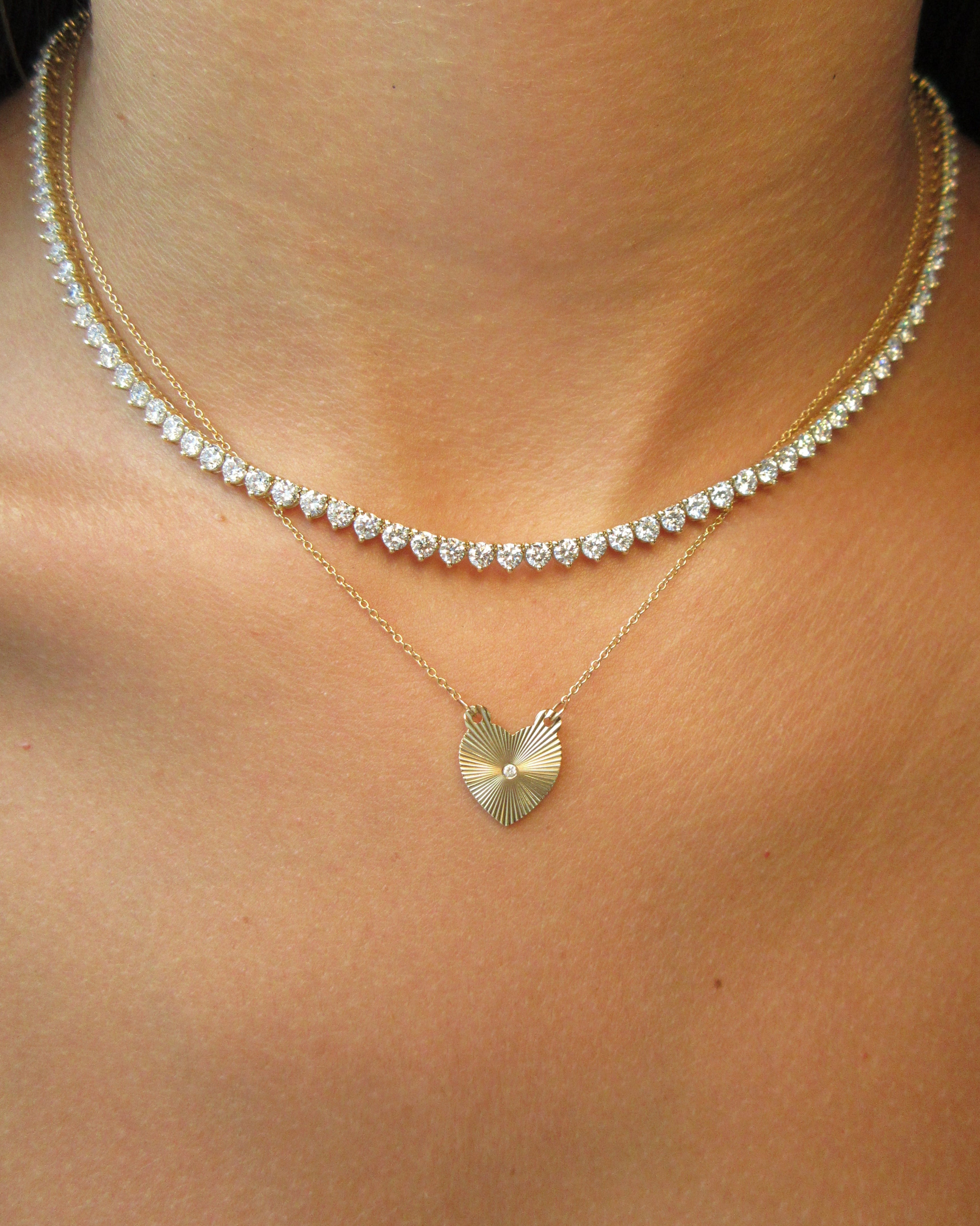 Gold necklace with a heart-shaped pendant on a person's neck