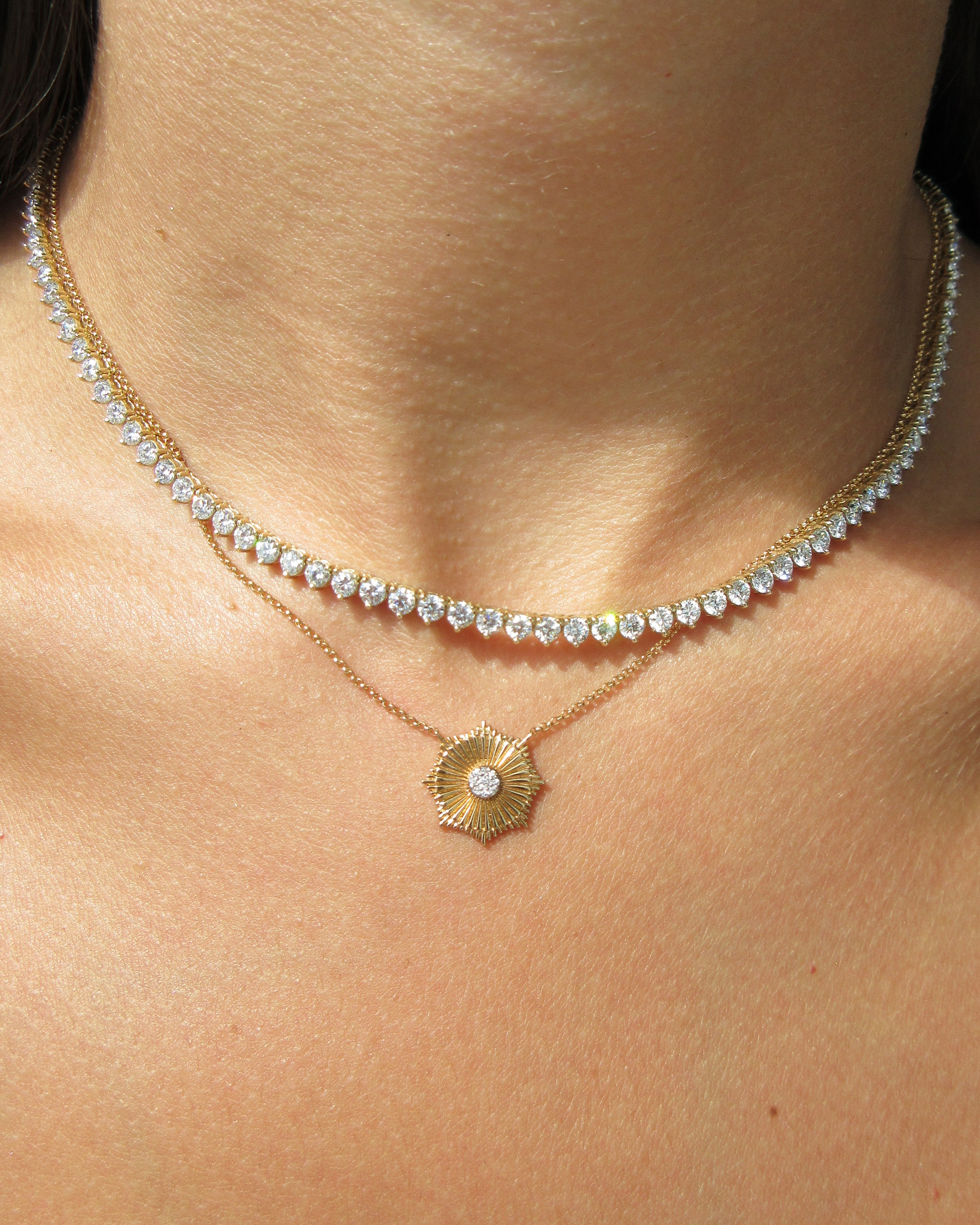 Close-up of a delicate gold and diamond necklace on a person's neck.