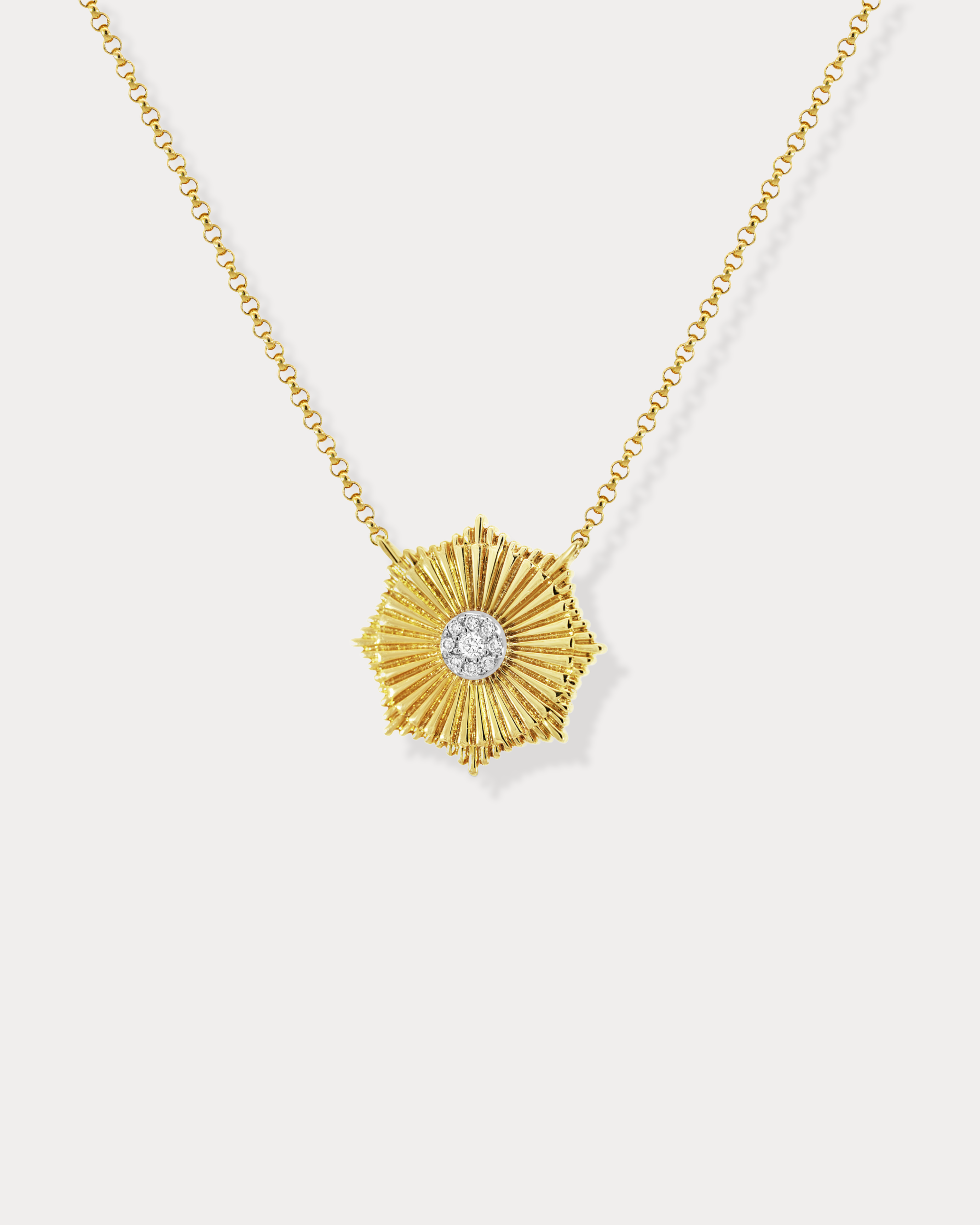 A gold-colored necklace with a sun-shaped fluted circle pendant accented with a sparkling diamond in the center.