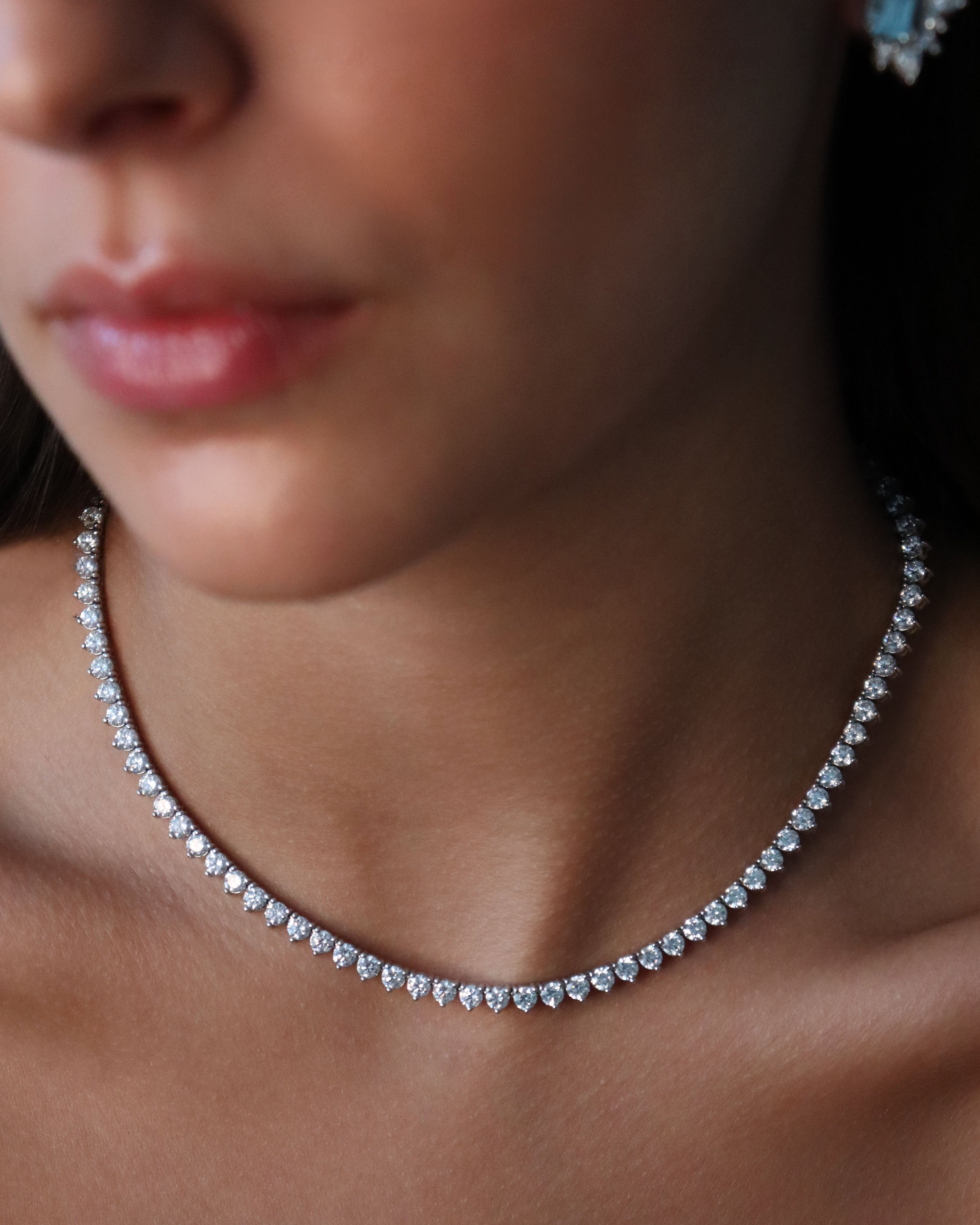 Close-up of a woman wearing a diamond necklace and earrings.