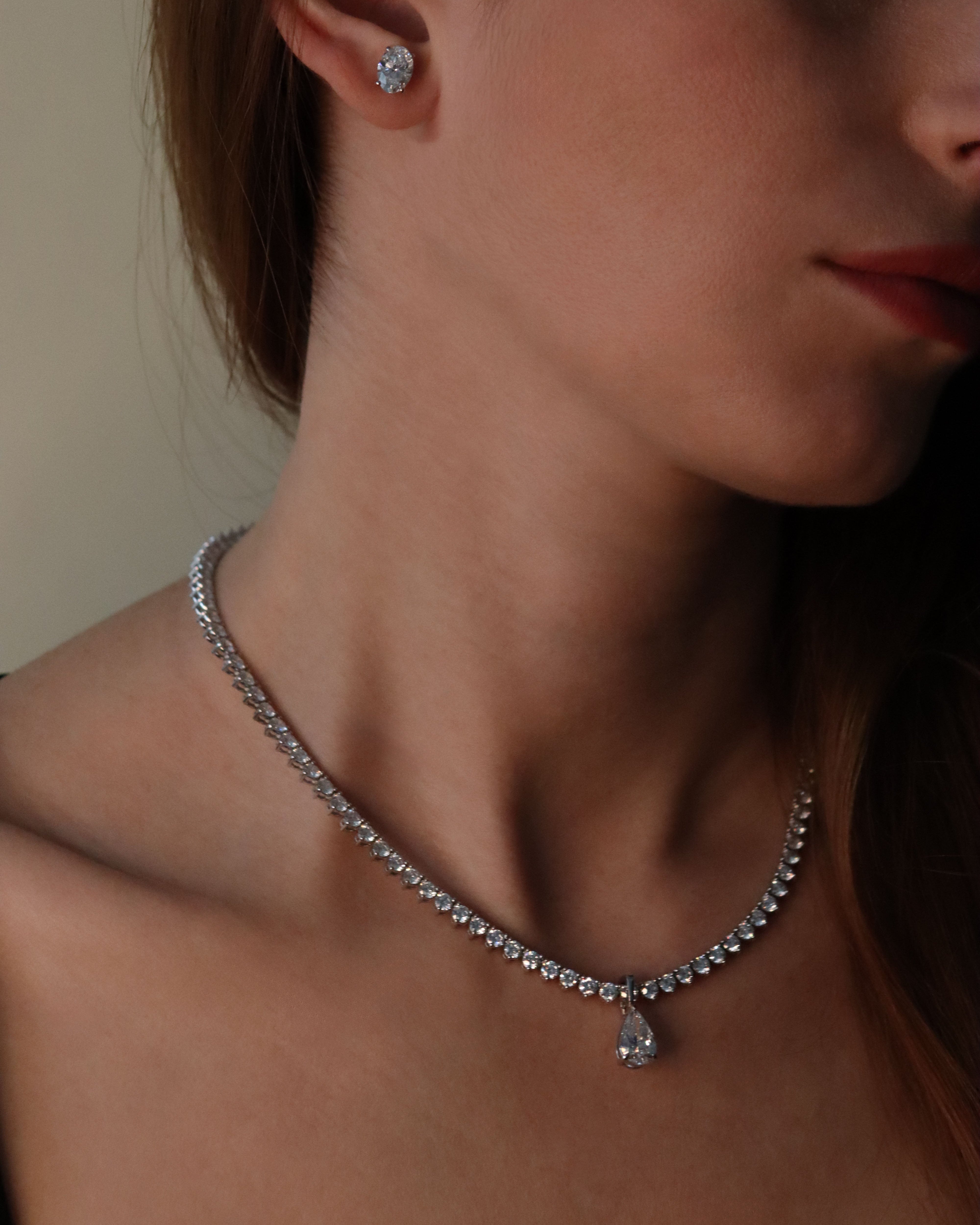 Close-up of a woman wearing a diamond necklace and earrings.