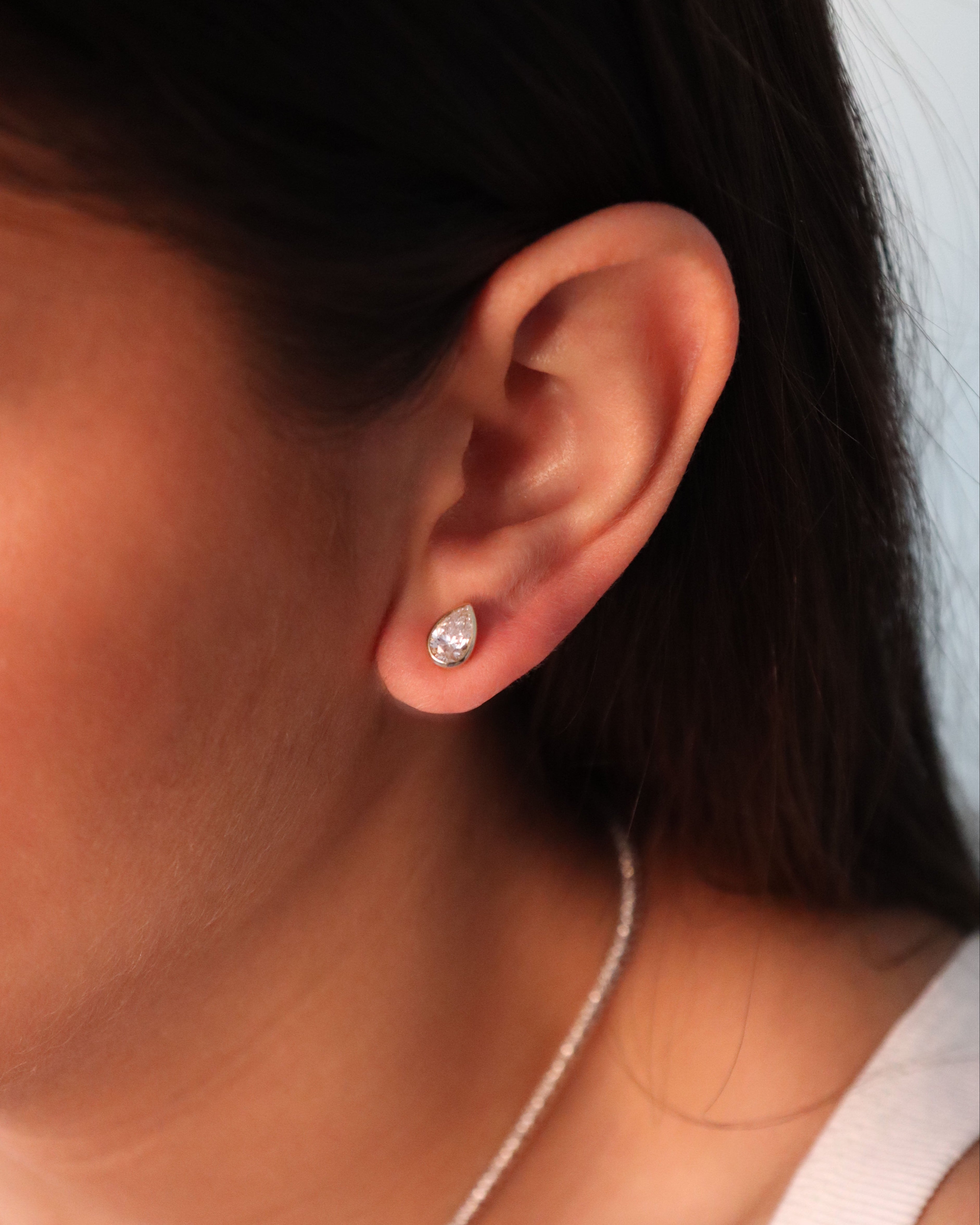 Close-up of an ear wearing a diamond earring with a blurred background