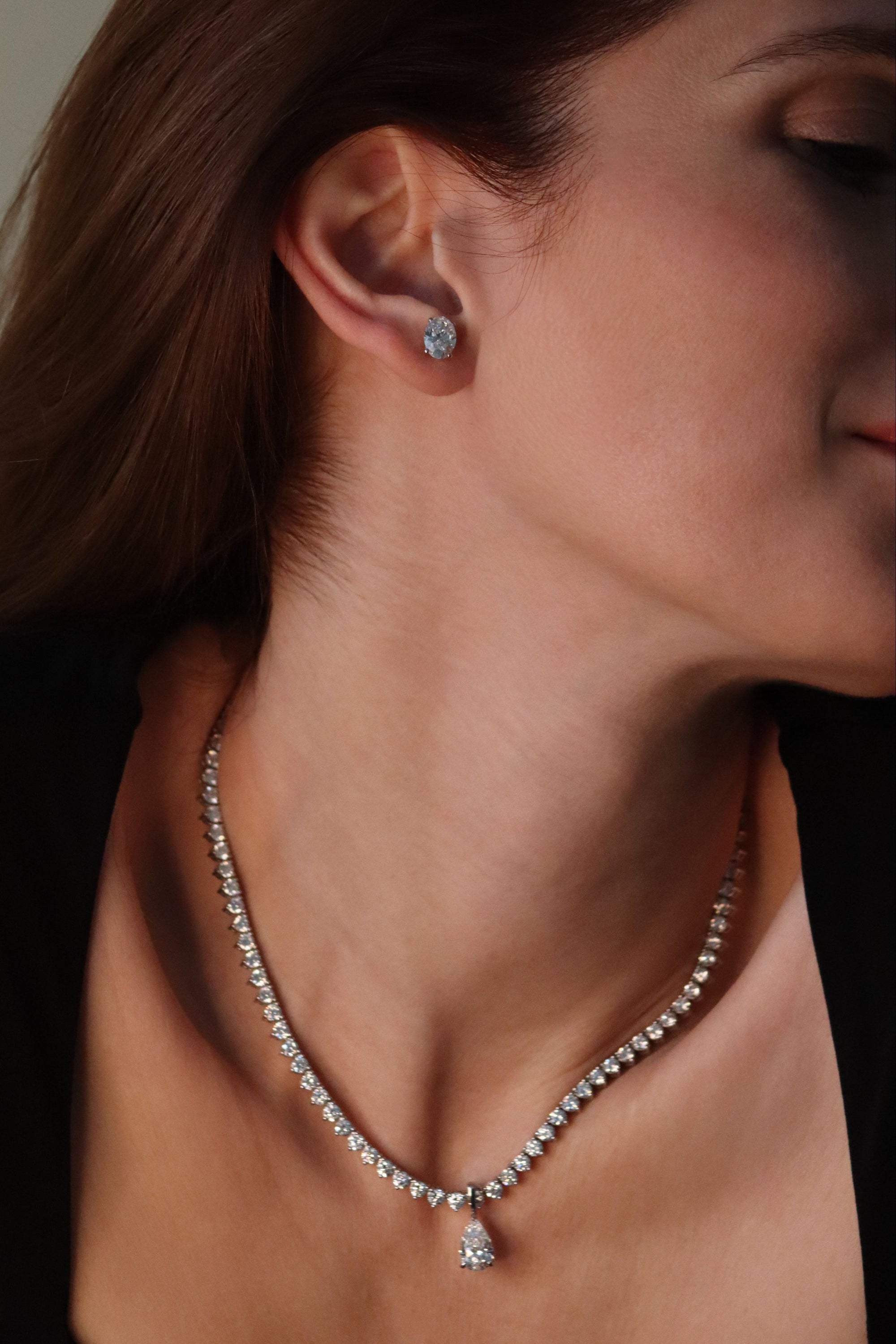 Close-up of a woman wearing a diamond necklace and earrings.
