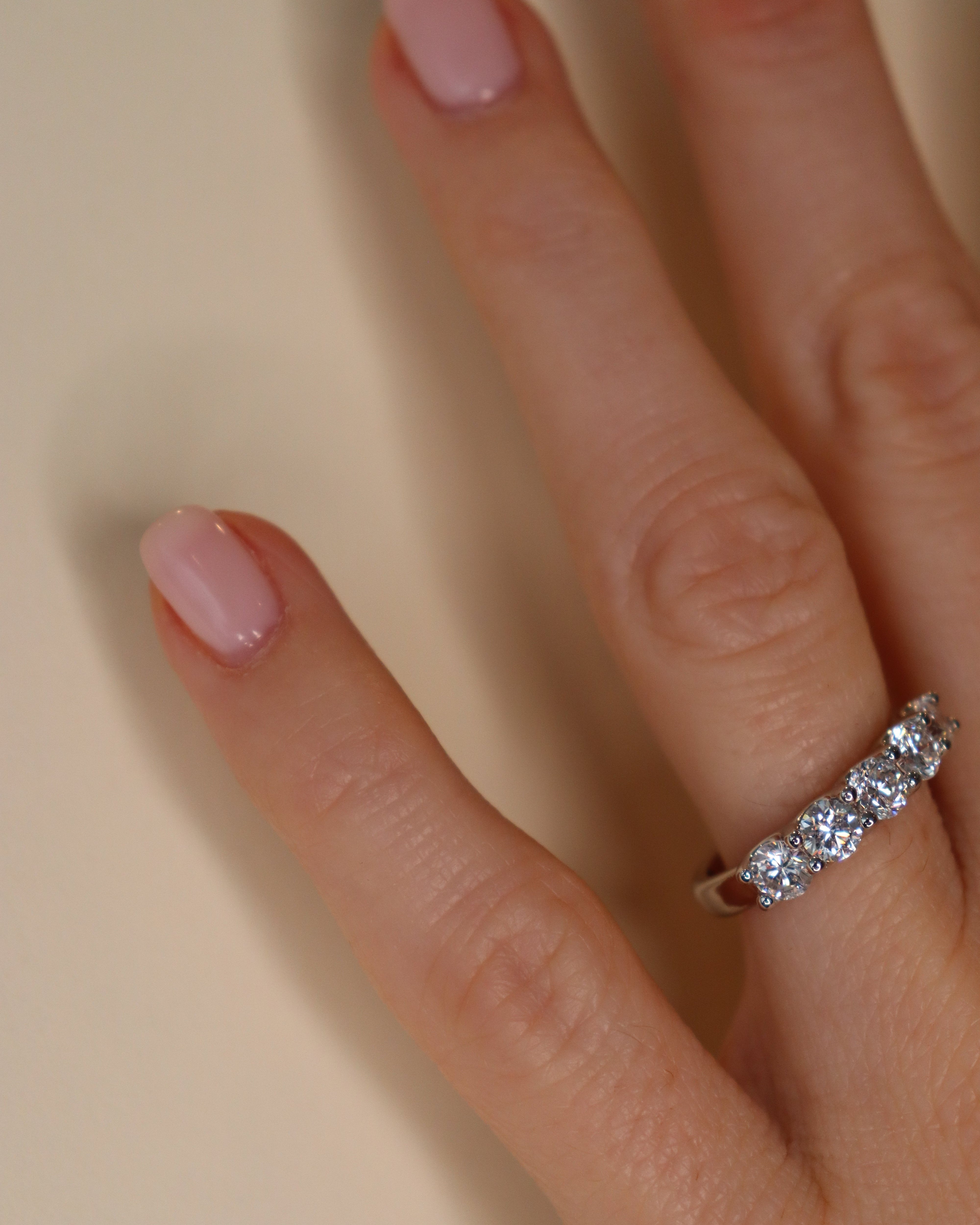 Hand wearing a diamond ring on a plain background