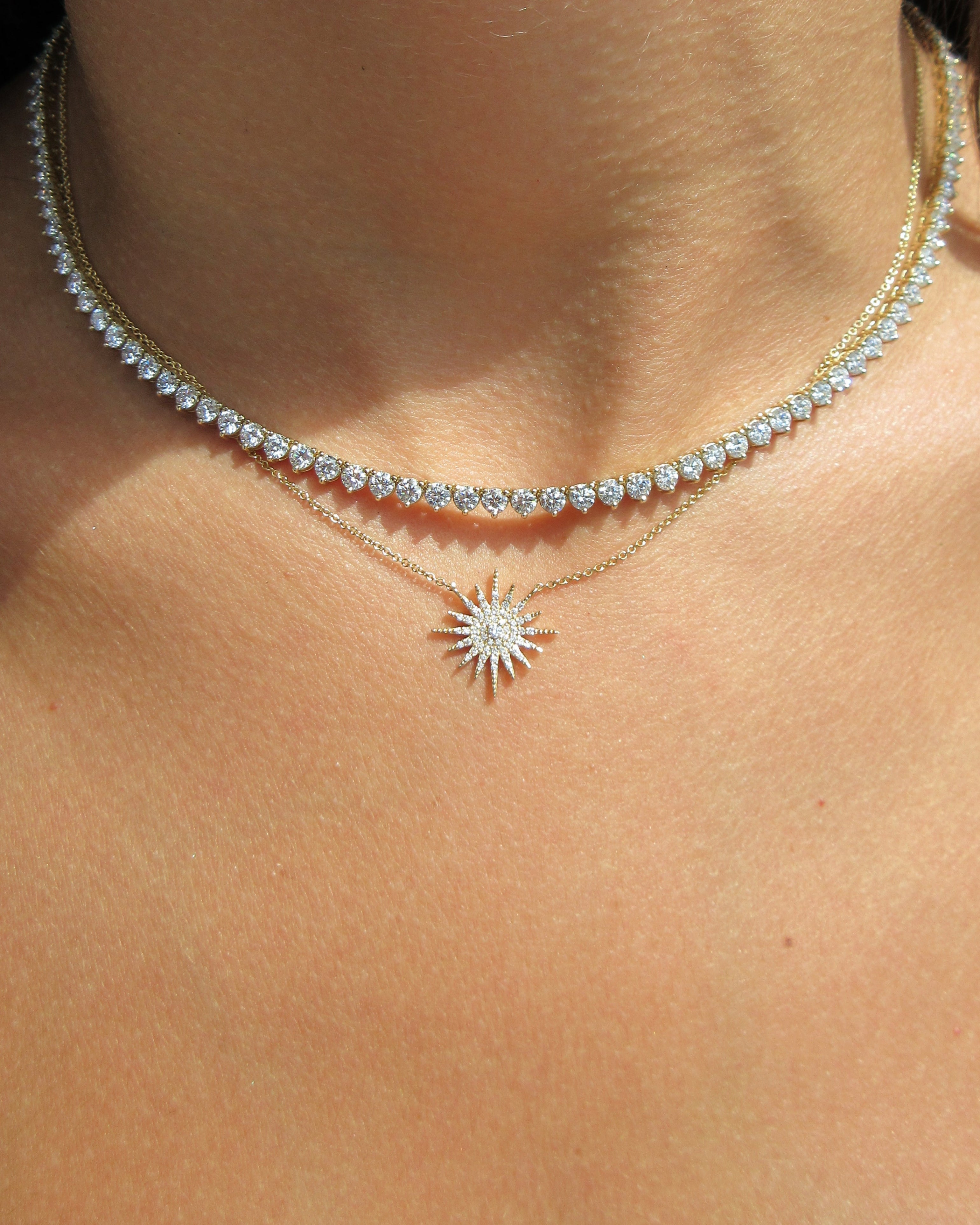 Close-up of a silver necklace with a sunflower pendant on a person's neck.
