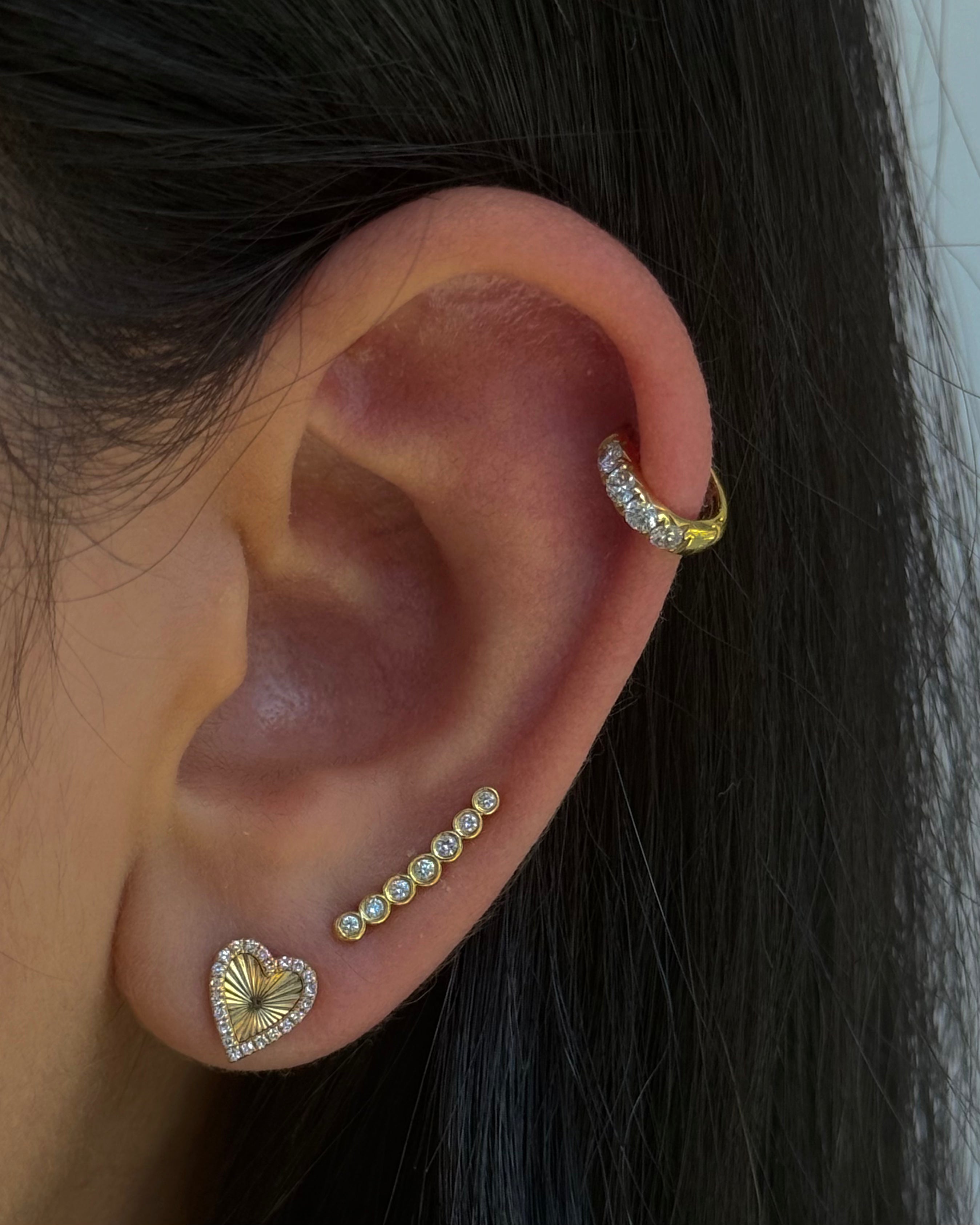 Close-up of an ear with gold and diamond earrings