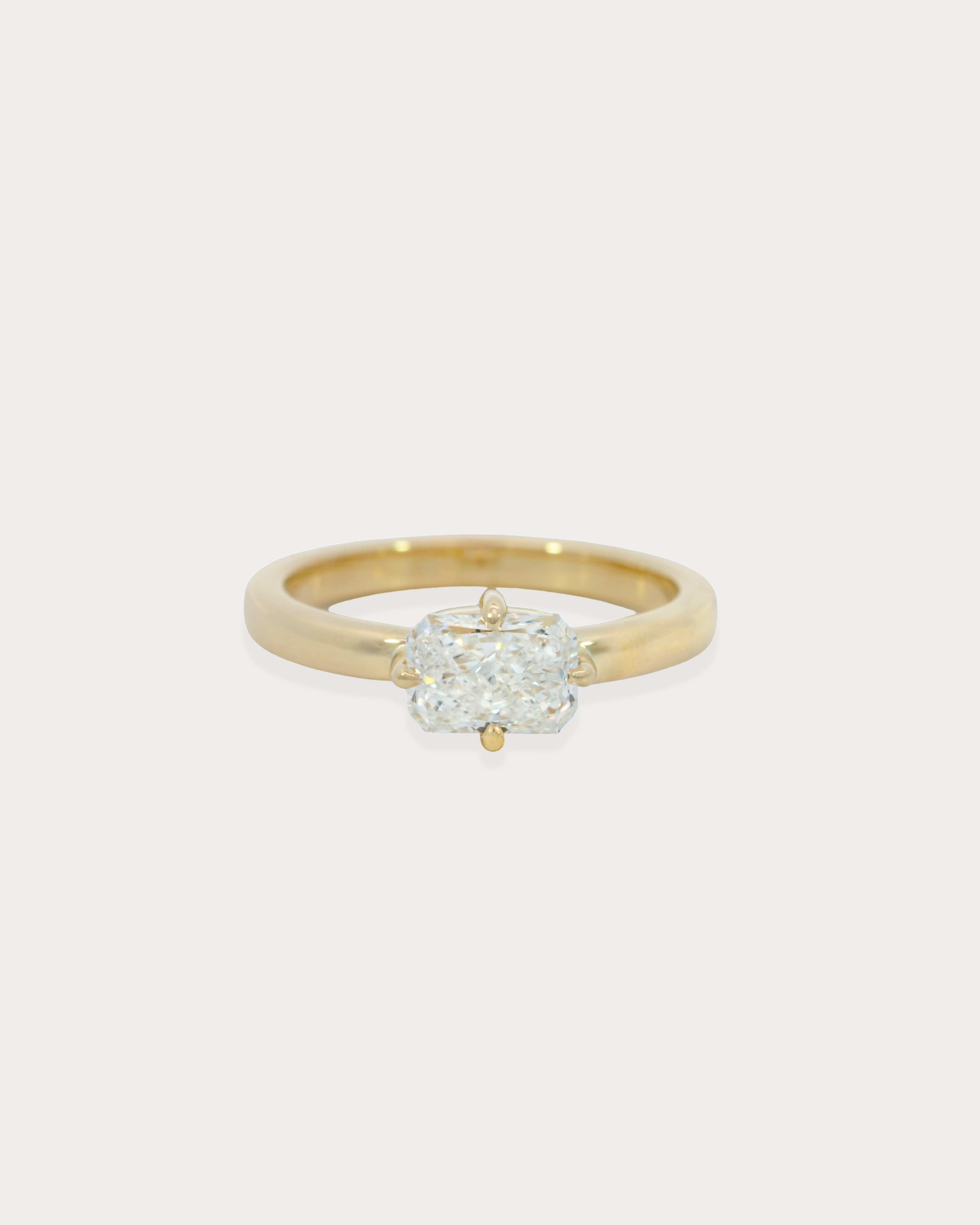 Gold ring with a diamond on a light beige background