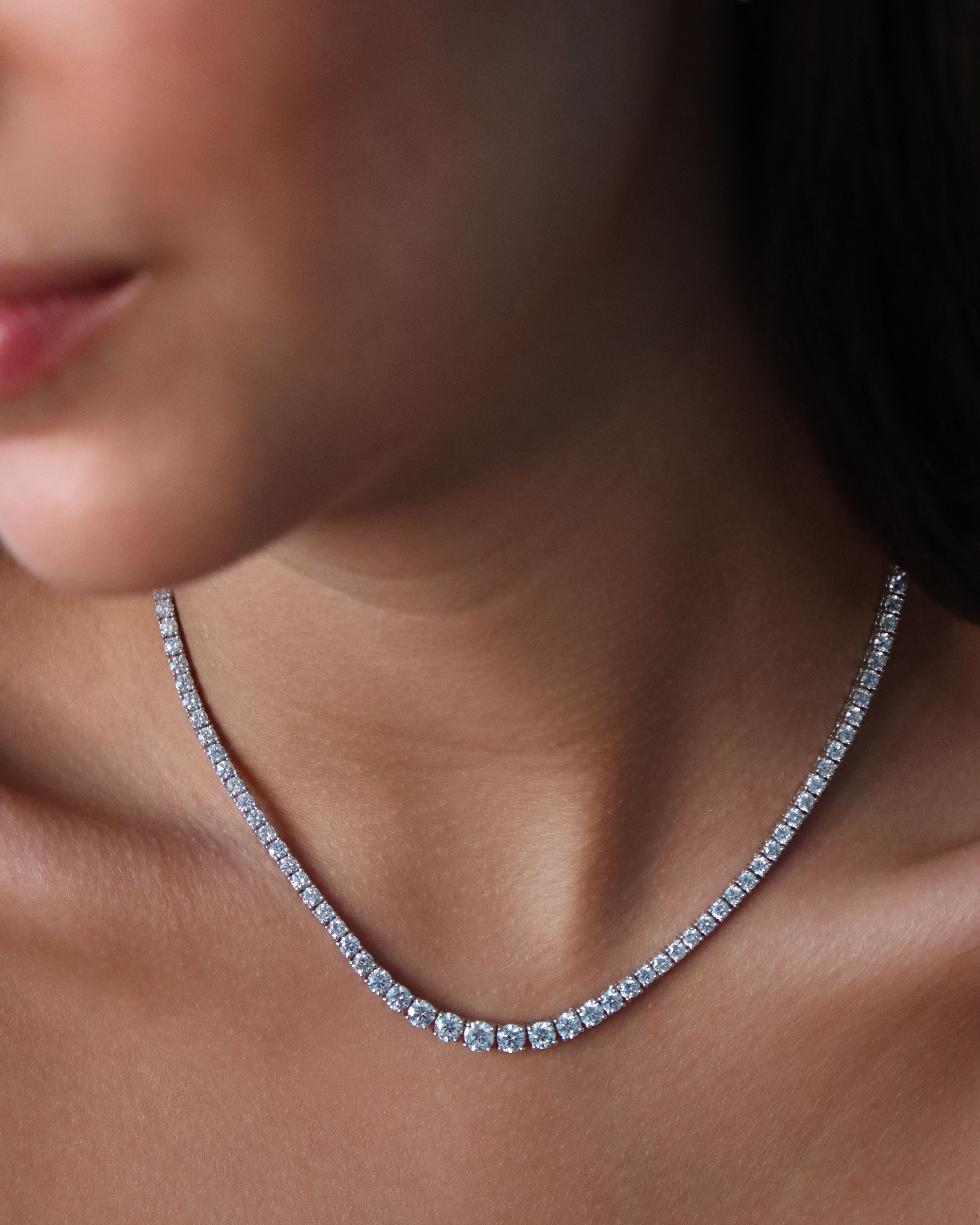 Close-up of a diamond necklace on a person's neck with a blurred background