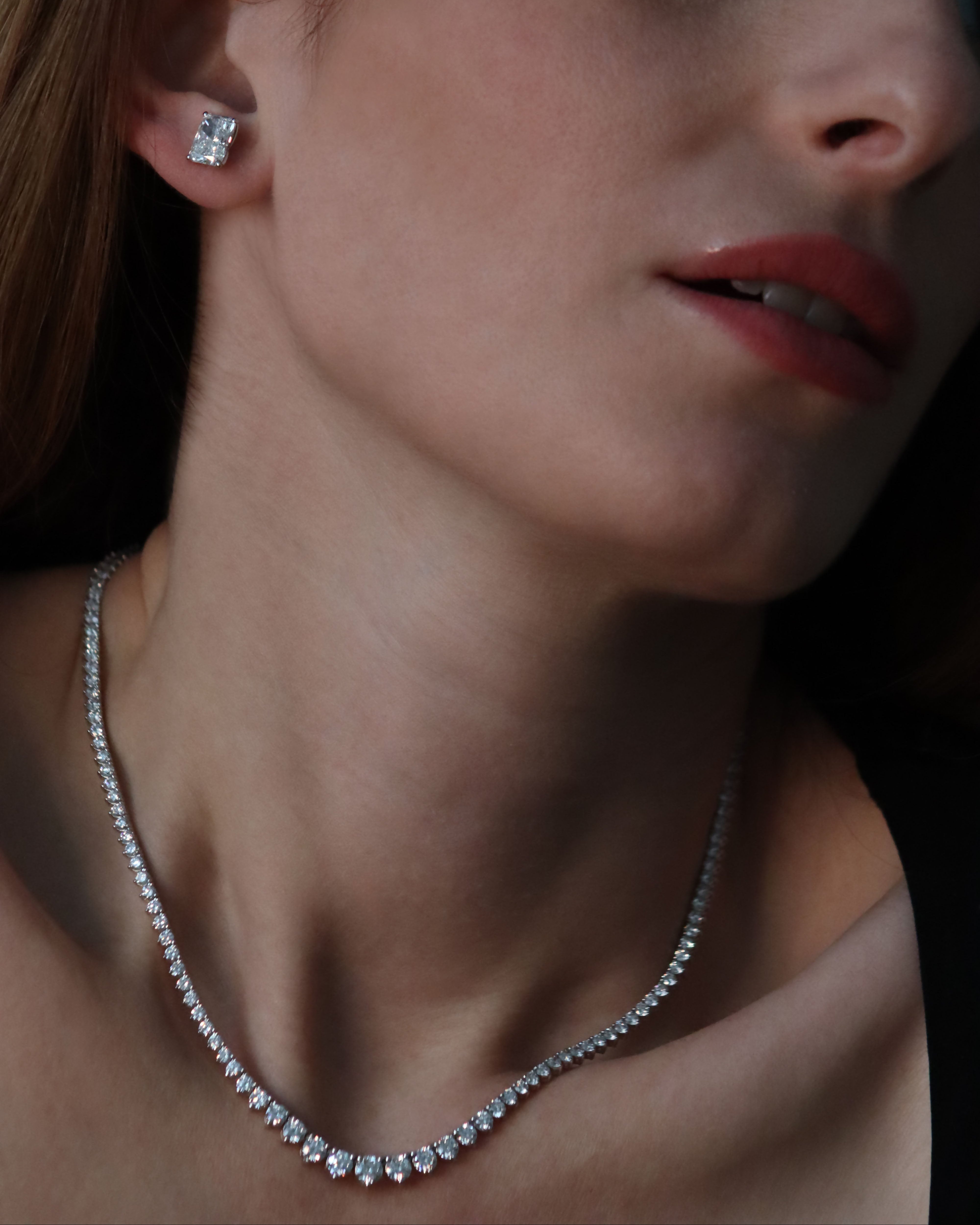 Close-up of a woman wearing diamond earrings and a necklace.