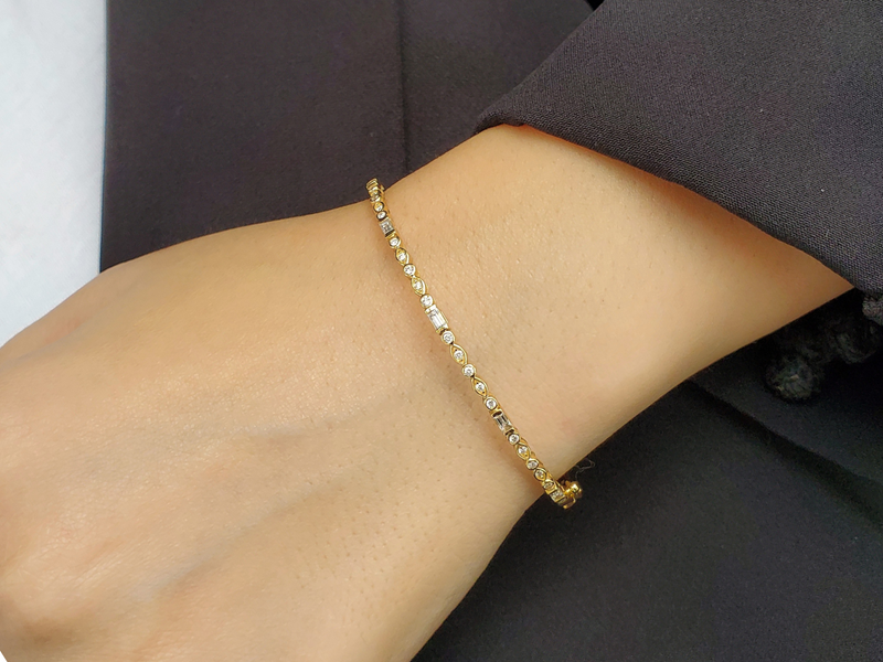 Round and baguette diamonds gold bangle with natural diamonds on a model, showcasing timeless elegance and modern sophistication.